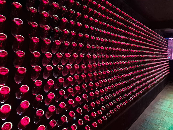 Antigua bodega con botellas rojas apiladas iluminadas en una bodega de Grecia - Foto, Imagen