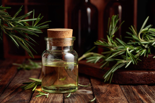Rosemary essential oil or infusion on an old wooden table. Aromatherapy, spa, and herbal medicine ingredients.  - 写真・画像