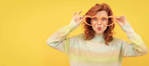 happy redhead girl wear funny party glasses on yellow background, party. Woman isolated face portrait, banner with copy space - Fotografie, Obrázek