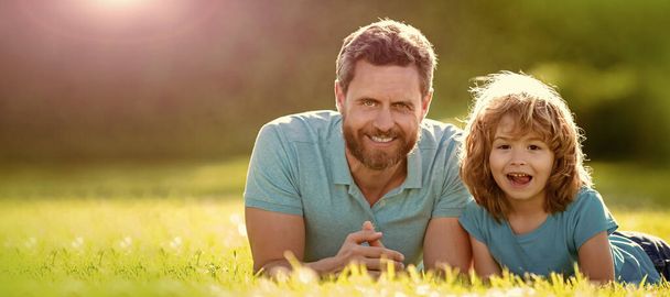 Banner of father and son in summer park outdoor. happy family of father and son kid relax in summer park green grass, togetherness. - Photo, Image