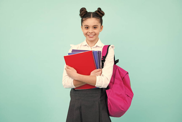 Boldog iskolás lány könyvvel és másolattal. Tinédzser iskoláslány diák, elszigetelt kék háttérrel. Tanulás és tudás. Menj tanulni. Oktatási koncepció - Fotó, kép