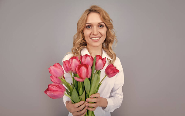 happy young woman holding spring tulip flowers on grey background. - Fotoğraf, Görsel
