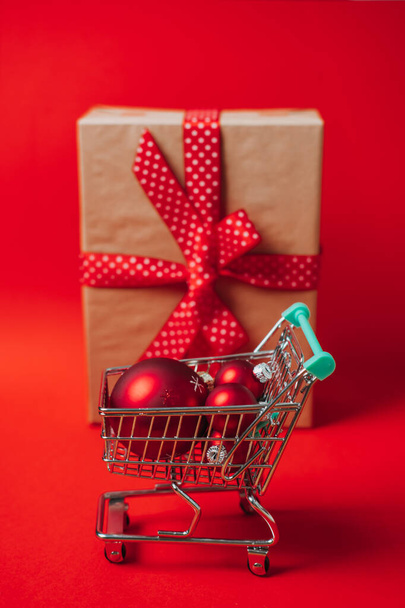 Різдвяний розпродаж Інтернет банер з міні-візком з подарунковою коробкою та червоними різдвяними прикрасами на червоному тлі. Мінімальна концепція продажу різдвяних покупок веб-банер копіювання простору
 - Фото, зображення