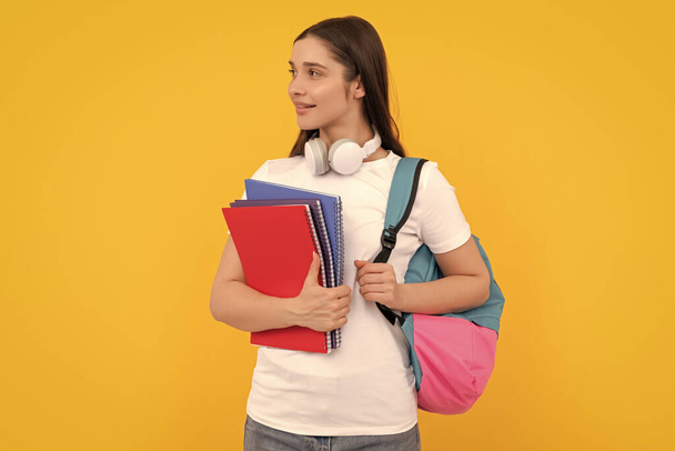pozitív tanulói jegyzetfüzet. lány kezében notebook sárga háttérrel. magántanár másolatokkal és fejhallgatóval. Vissza az iskolába. modern oktatási koncepció. - Fotó, kép