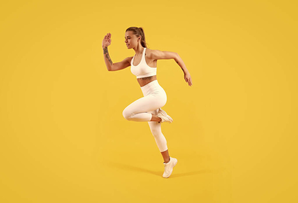 fitness girl jumping in sportswear on yellow background. - Foto, Imagem