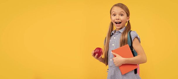 Surprised girl child hold tasty apple for healthy back to school snack, school fruit. Banner of schoolgirl student. School child pupil portrait with copy space - Фото, изображение