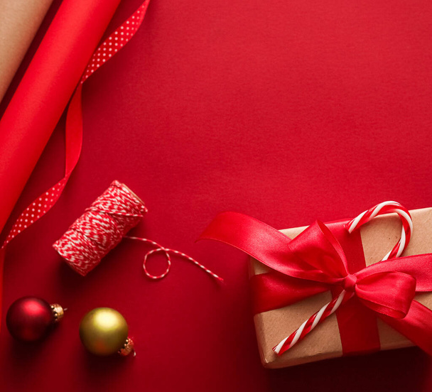 Χριστουγεννιάτικη προετοιμασία, την ημέρα πυγμαχίας και τις γιορτές δώρο δίνοντας, χριστουγεννιάτικο χαρτί χειροτεχνίας και κορδέλες για τα δώρα κουτιά σε κόκκινο φόντο ως εργαλεία περιτύλιξης και διακοσμήσεις, diy παρουσιάζει ως διακοπές επίπεδη lay σχεδιασμό - Φωτογραφία, εικόνα