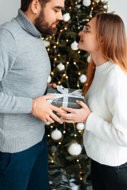 Cute, young couple exchanging Christmas gifts for Christmas morning. - Foto, imagen