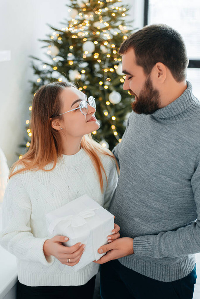 Cute, young couple exchanging Christmas gifts for Christmas morning. - Zdjęcie, obraz
