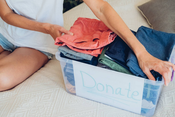 Woman sorts wardrobe indoors at home. Charity donation concept. High quality photo - Photo, Image