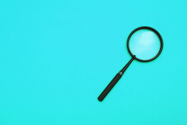 Loupe or magnifying glass on a turquoise background. Shallow depth of field - Photo, image