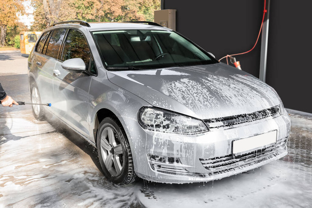 Man washing auto with high pressure water jet at outdoor car wash, closeup - Foto, immagini