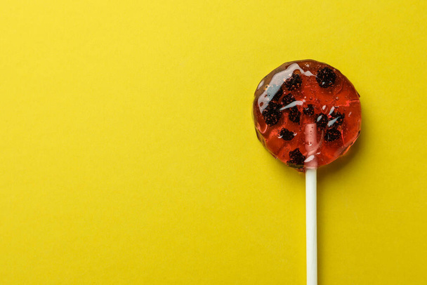 Sweet colorful lollipop with berries on yellow background, top view. Space for text - Fotografie, Obrázek