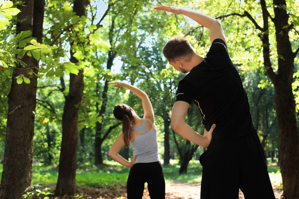 Man and woman doing morning exercise in park, back view - Fotografie, Obrázek