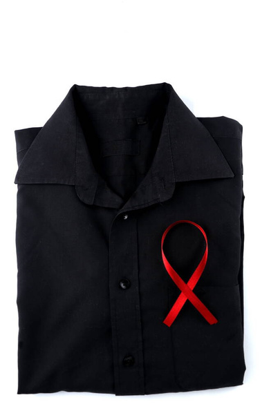 Red ribbon on a black shirt on a white background. Modern treatment and healthcare. AIDS awareness concept. - 写真・画像