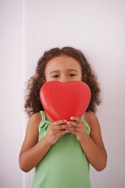 If I give you my heart please dont break it. a young girl smiling as she holds a heart shaped toy - Foto, immagini