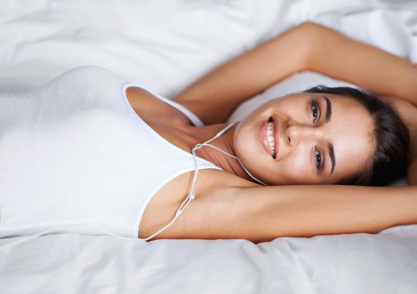İzin günümde boş zamanım. Yatağında yatarken müzik dinleyen güzel bir genç kadının portresi. - Fotoğraf, Görsel