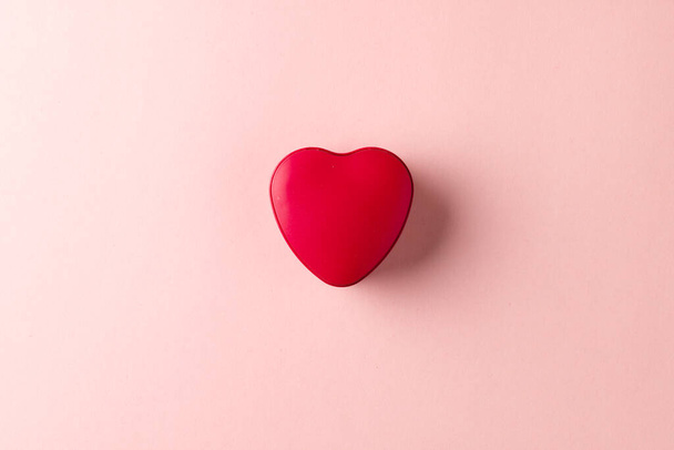 Overhead of red heart shaped box on pale pink background with copy space. Valentine's day, love, romance and celebration concept. - Foto, imagen
