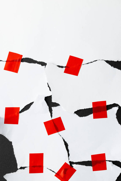 Ripped up pieces of white paper stuck together with red tape with copy space on black background. Abstract paper texture background and communication concept. - Photo, Image