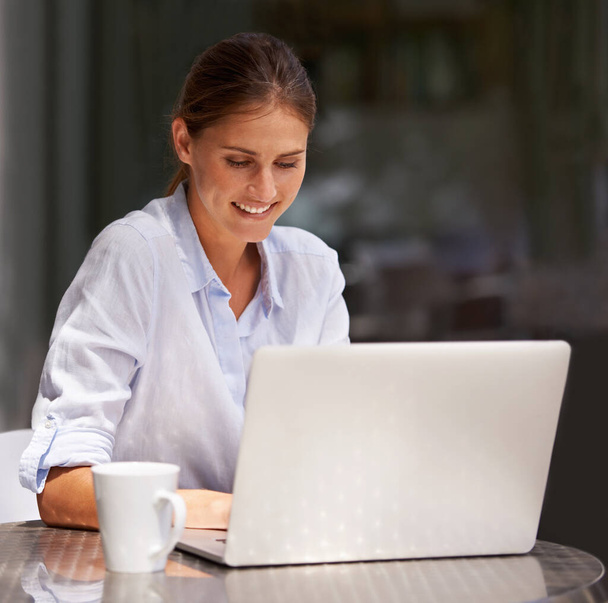 Trabajar afuera al aire libre la hace sonreír. una atractiva joven usando su portátil al aire libre - Foto, Imagen