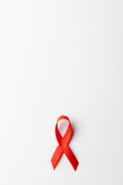 Vertical composition of red ribbon for hiv or aids awareness, on white background with copy space. Medicine, healthcare and health awareness concept. - 写真・画像