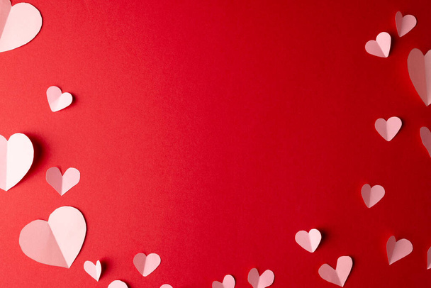 White paper heart shapes, on red background with central copy space. Valentine's day, love, romance and celebration concept. - Фото, изображение