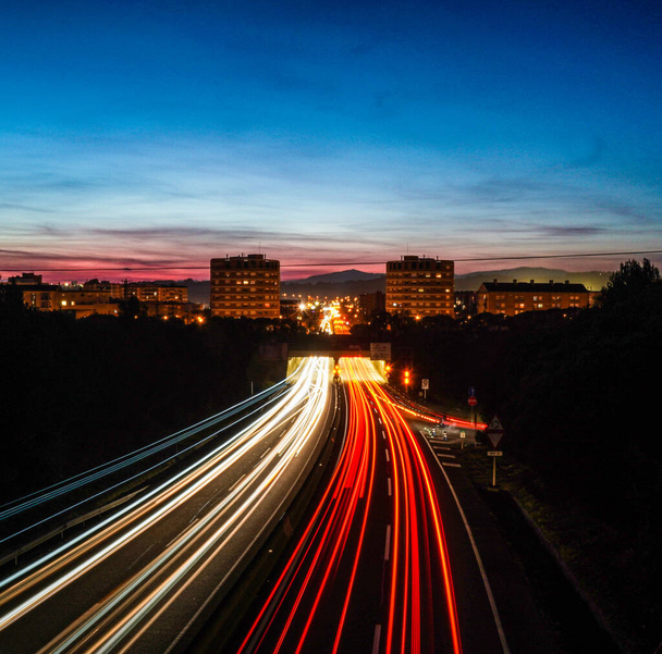 Promienie światła, w zwolnionym tempie, samochodów jadących po autostradzie w nocy, aby wejść i opuścić miasto Granollers, Barcelona. - Zdjęcie, obraz