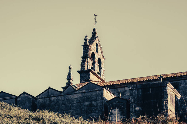 Detalhe da Igreja e do cemitério de uma aldeia galega sob o pôr do sol de uma colina. - Foto, Imagem