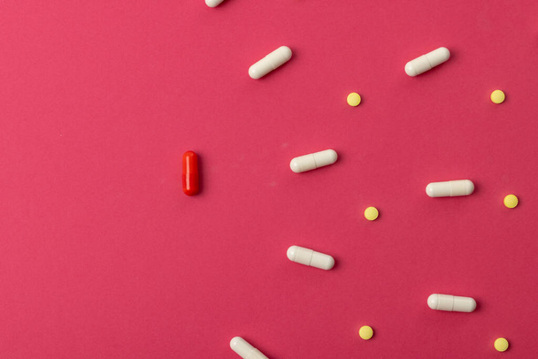 Composition of various pills on red background with copy space. Medicine, medical services, healthcare and health awareness concept. - 写真・画像