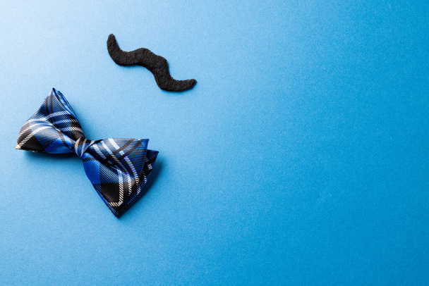Composition of fake moustache and bow tie on blue background with copy space. Fake moustache day, party, celebration and costume concept. - Valokuva, kuva