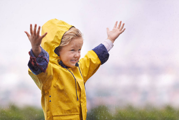 Yağmur yağsa da yağmasa da hayatı sevmek. Dışarıda yağmurda oynayan sevimli küçük bir kız. - Fotoğraf, Görsel