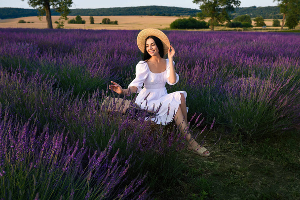 Beautiful young woman sitting in lavender field - Fotó, kép