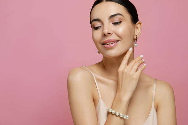 Young woman wearing elegant pearl jewelry on pink background, closeup. Space for text - Foto, afbeelding
