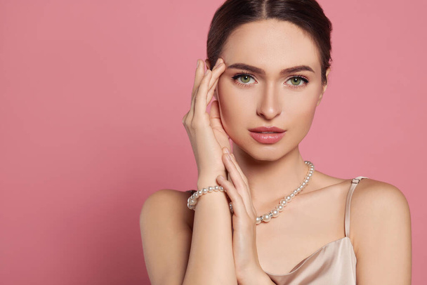 Young woman wearing elegant pearl jewelry on pink background, space for text - Fotoğraf, Görsel