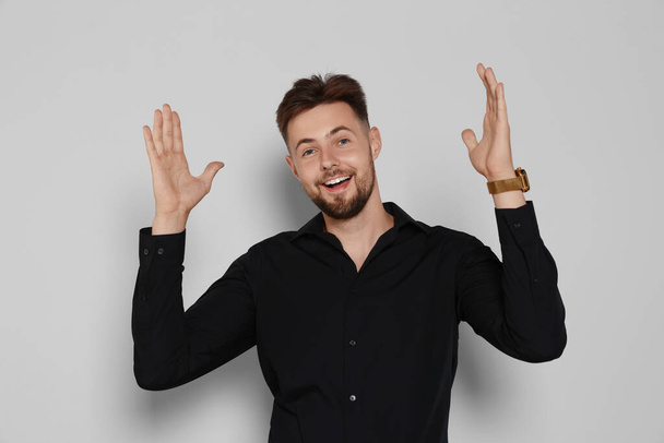 Excited man in black shirt on light grey background - Photo, Image