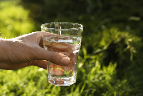 Man holding glass of fresh water outdoors, closeup - Zdjęcie, obraz