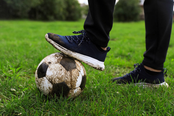 Man with dirty soccer ball on green grass outdoors, closeup - Foto, Imagem