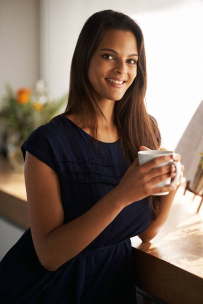 Lets get this day started. an attractive young woman standing in her kitchen while drinking coffee - Фото, изображение