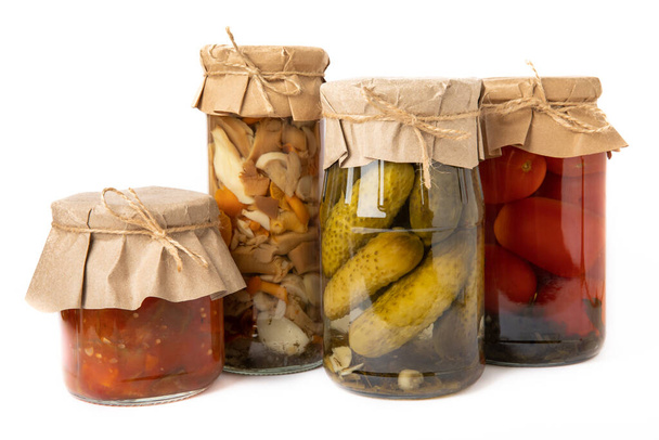 Preservation of vegetables in jars. Fermentation products. Harvesting of tomatoes and cucumbers, mushrooms, salads for the winter. Jars with pickled vegetables. Isolated on a white background. - Foto, imagen