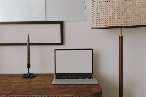 Laptop computer with blank copy space screen on table with candles, mirror and lamp. Aesthetic home office workspace. Online shopping, online store, social media, blog branding mockup template. - Photo, Image