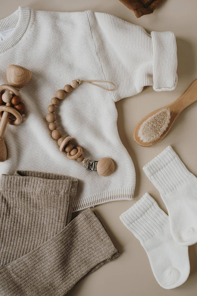Pastel beige gezellige elegante stijlvolle Scandinavische pasgeboren baby kleding en eco accessoires. Online modewinkel, online shopping branding concept. Trui, beenkappen, sokken, borstel, fopspeen houder - Foto, afbeelding