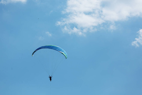Mavi Paraglider güneşli bir günde bulutlarla gökyüzüne uçuyor.. - Fotoğraf, Görsel