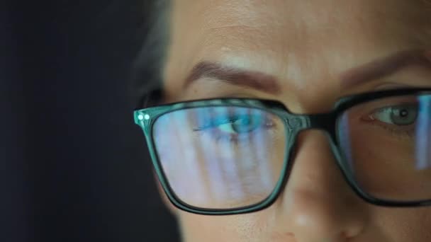 Woman in glasses looking on the monitor and working with charts and analytics. The monitor screen is reflected in the glasses. Work at night. Extreme close-up. - Séquence, vidéo
