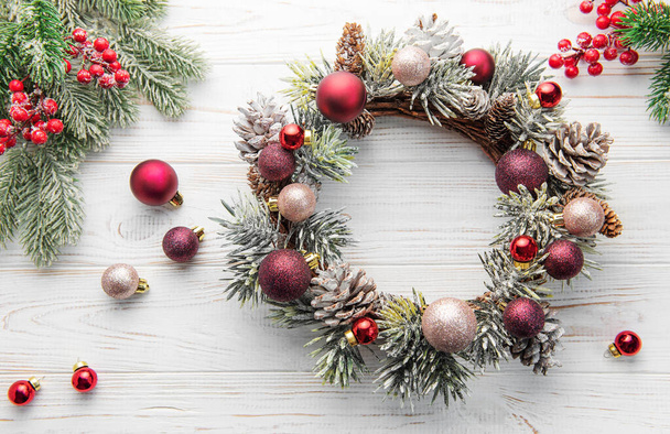 装飾的なクリスマスの花輪。白い木製の背景に赤と金色のクリスマスのおもちゃでリース.  - 写真・画像