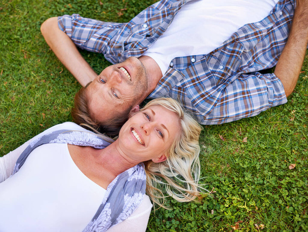 A olhar para o céu. Tiro de ângulo alto de um casal atraente deitado ao ar livre na grama - Foto, Imagem