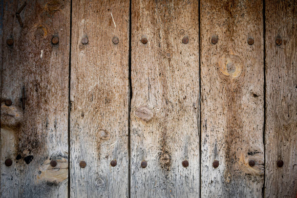 Старі двері старого одного листа з металевими прикрасами на натуральному незабарвленому дереві
 - Фото, зображення
