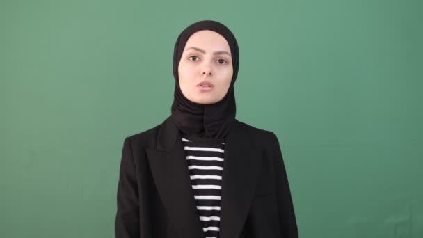イスラム教徒の女性は静かで、女の子はクロマキーの前で話すのを停止し、顔の表情深刻な、隔離された緑の背景 - 映像、動画