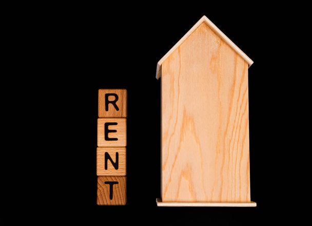 деревянный макет дома с ключами от дома, деревянные кубики со словами арендная продажа, покупка и кредит. Проект для дизайнера на черном фоне - Фото, изображение