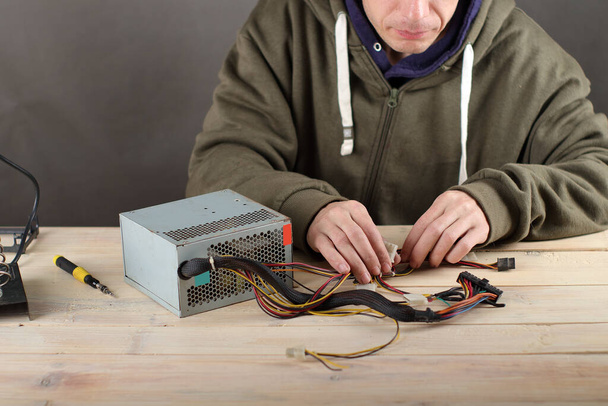 person checking computer power supply on table and gray background - Φωτογραφία, εικόνα