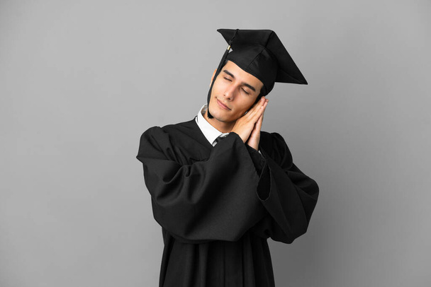 Young Argentinian university graduate isolated on grey background making sleep gesture in dorable expression - Φωτογραφία, εικόνα